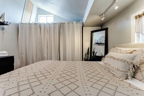 A bedroom with a large bed, a nightstand, a mirror, and a window with curtains. - Pet-Friendly House w/ Backyard & Free Parking (Springfield)