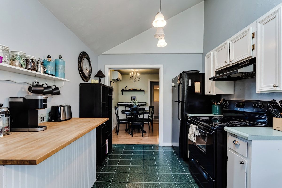 A compact kitchen with a coffee maker, a stove, and a dining area with a table and chairs.