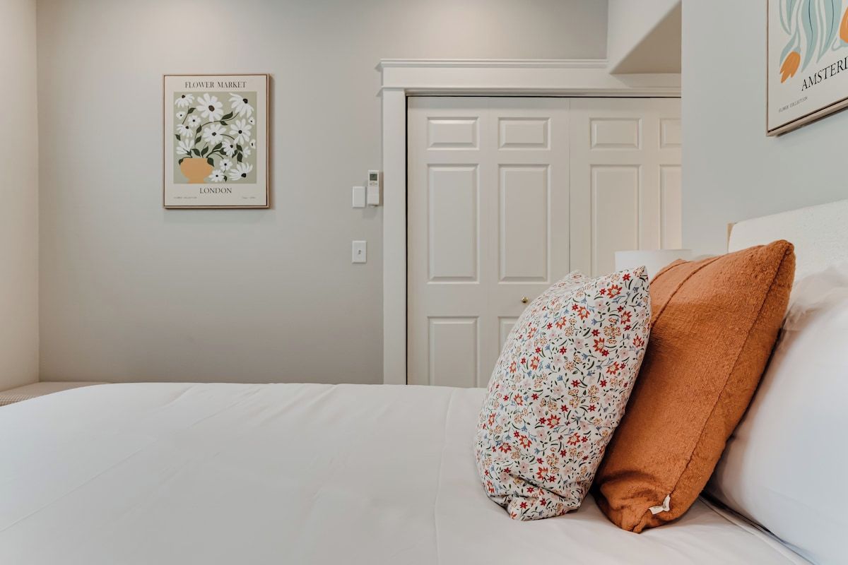 Une chambre à coucher avec un lit, une porte et deux tableaux encadrés au mur.