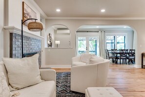 A living room with a fireplace, a sofa, a chair, and a dining area with a table and chairs.