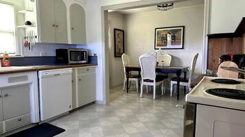 A kitchen with white cabinets, a microwave, a stove, and a dining area with a table and chairs.