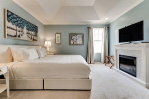 A bedroom with a large bed, a television, a fireplace, and artwork on the walls. - Stylish House w/ Backyard & Free Parking (Eugene)