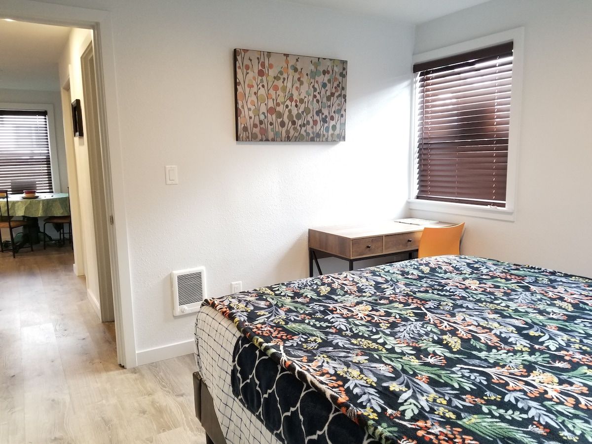 Quarto com cama, escrivaninha e janela com persianas.