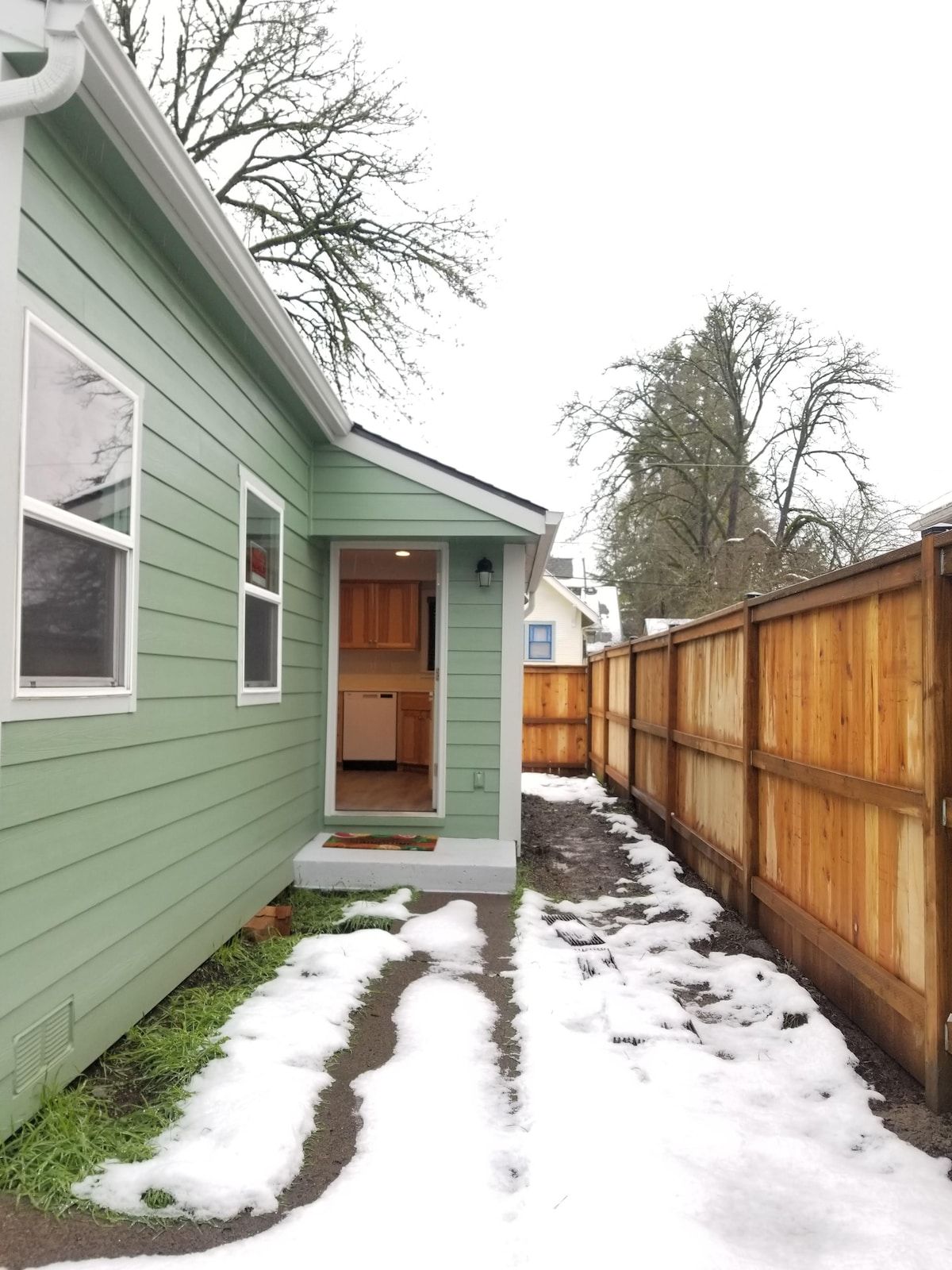 A green house with a visible kitchen area and a wooden fence.