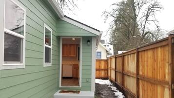 A green house with a visible kitchen area and a wooden fence.