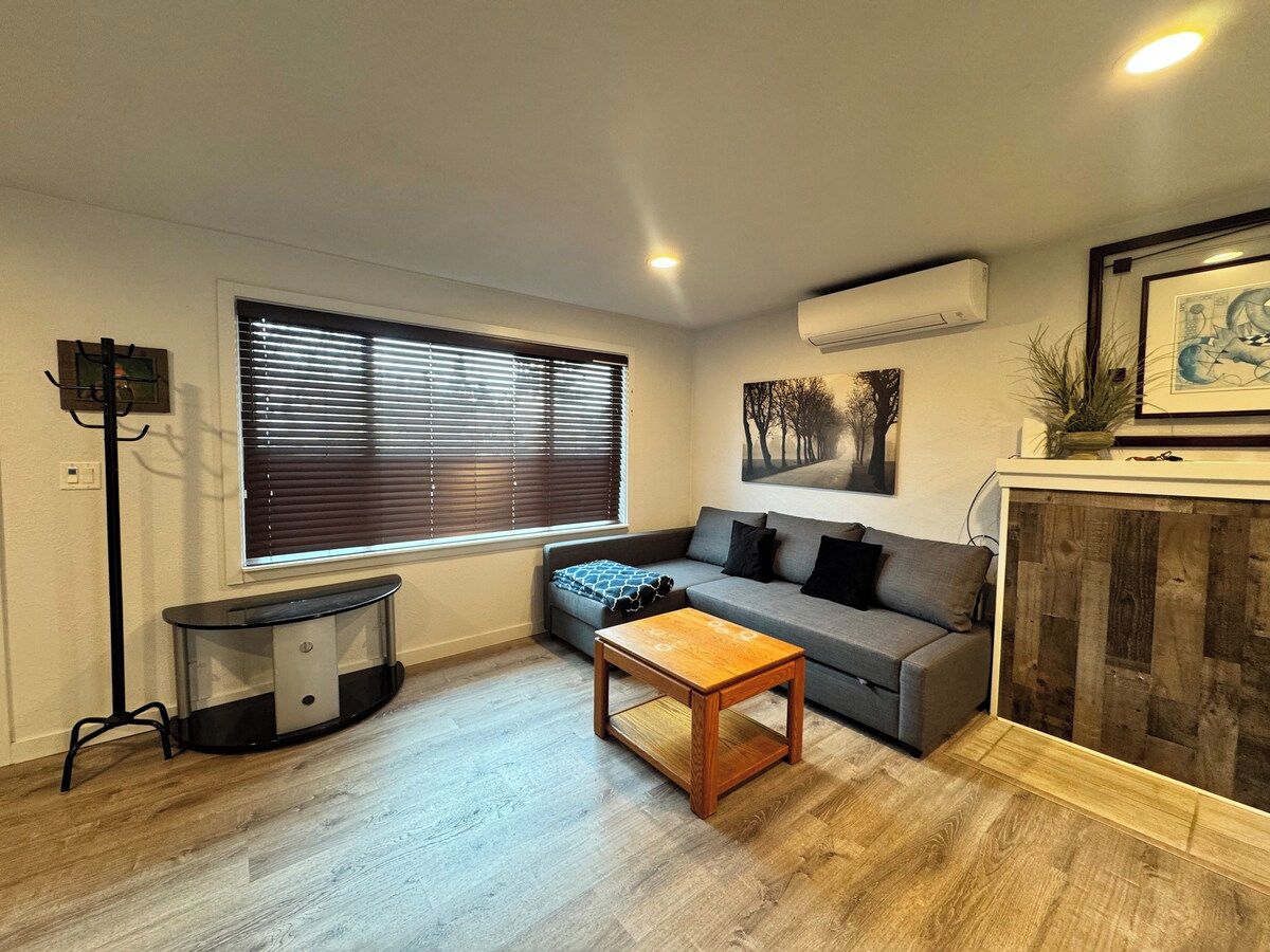 A living room with a sofa, a coffee table, a TV stand, and a fireplace.