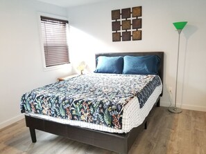 Ein Schlafzimmer mit einem Bett, einem Nachttisch, einer Lampe und einer Wanddekoration.
