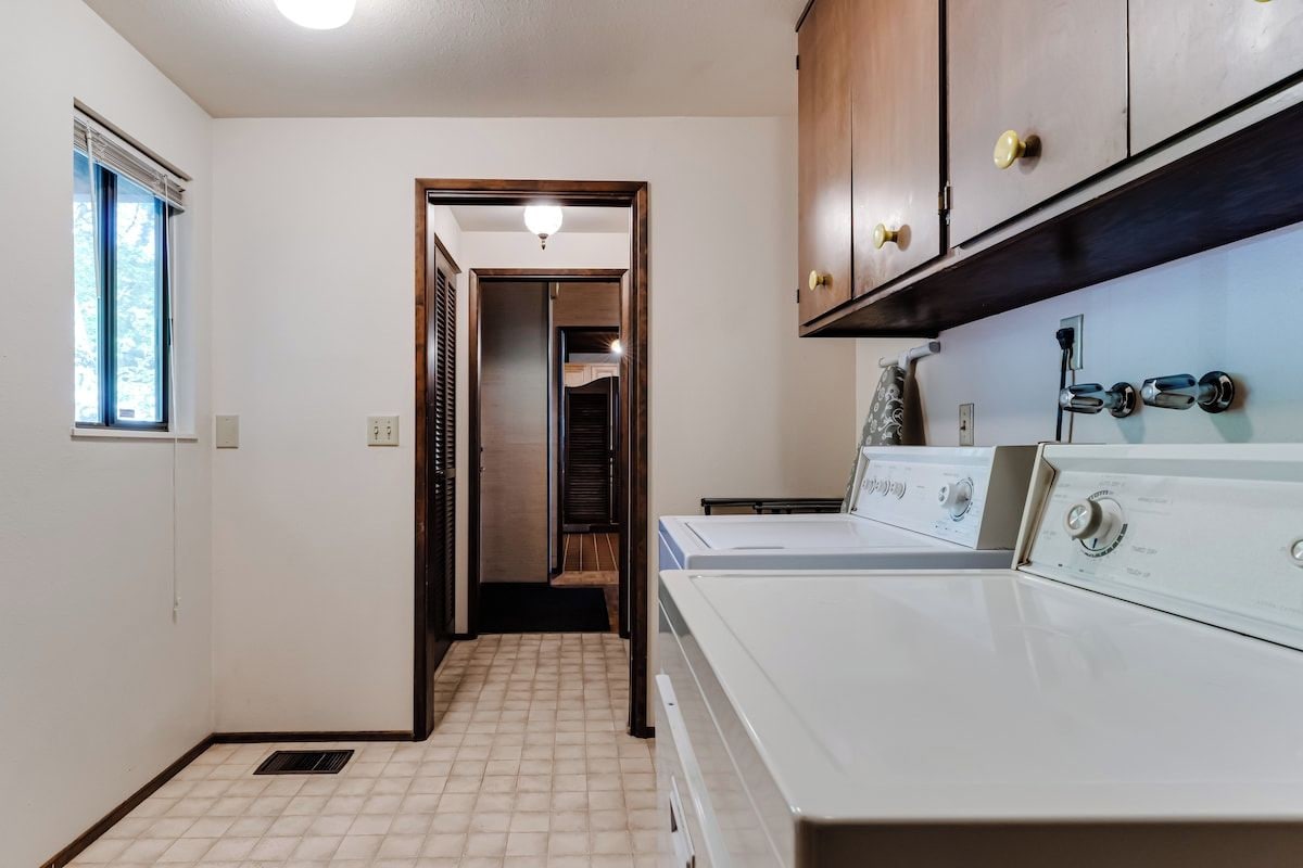 A laundry room with a washing machine, a dryer, and wooden cabinets.
