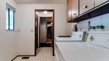A laundry room with a washing machine, a dryer, and wooden cabinets.