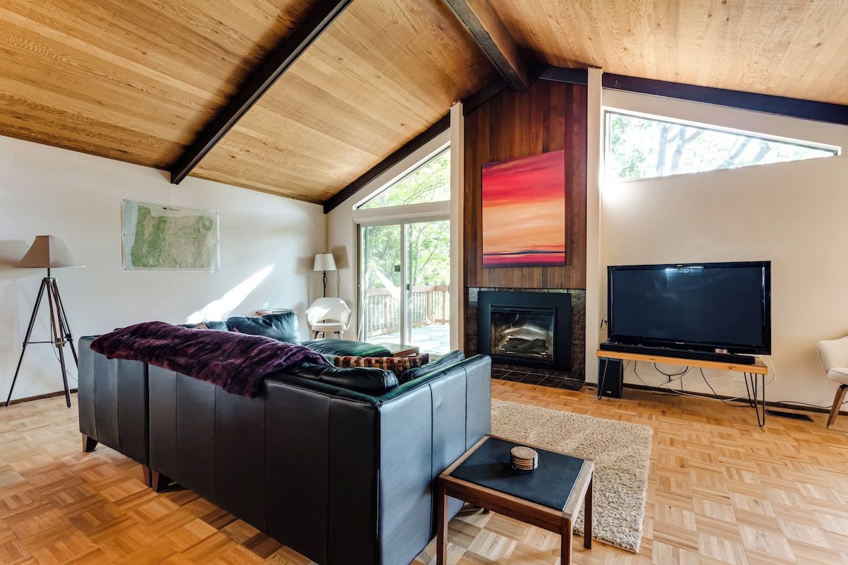 Ein modernes Wohnzimmer mit Kamin, großem Flachbildfernseher und einer Couch.