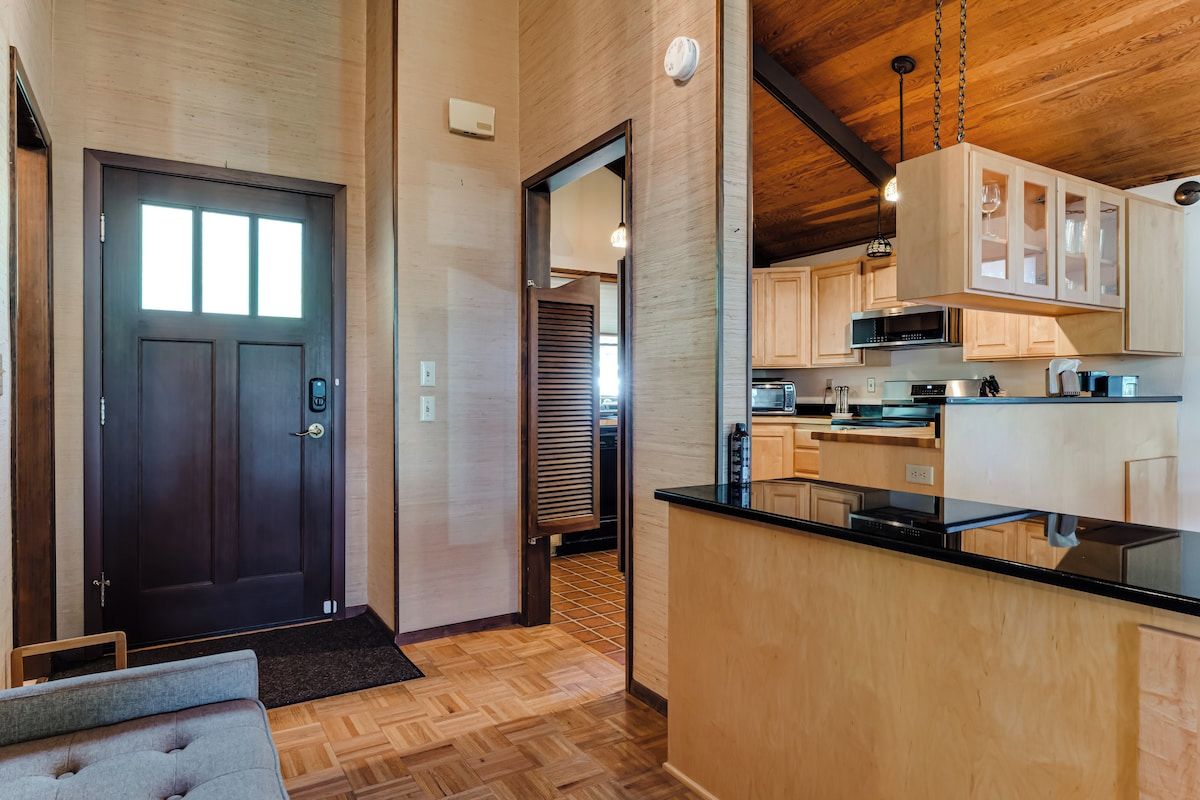 A modern kitchen with wooden cabinets, a black countertop, and a microwave.