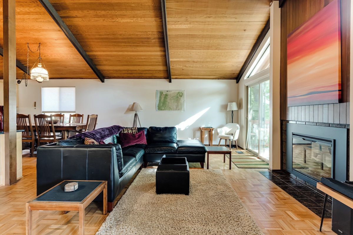 Ein geräumiges Wohnzimmer mit einer schwarzen Ledersofa, einem Holztisch und einem Kamin.