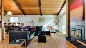 Ein geräumiges Wohnzimmer mit einer schwarzen Ledersofa, einem Holztisch und einem Kamin.