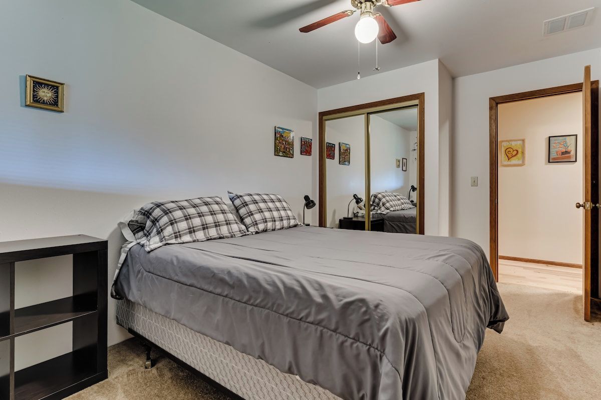 Une chambre à coucher comprenant un lit, un ventilateur de plafond, une armoire et une table de chevet.