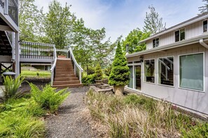 A modern house with a covered outdoor staircase, a well-maintained garden, and a large windowed structure. - Waterfront Studio Apartment w/ Balcony & Lake (Veneta)