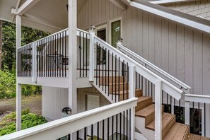 Ein zweistöckiges Haus mit weißer Fassade, einer Holztreppe und einem Balkon mit Geländer.