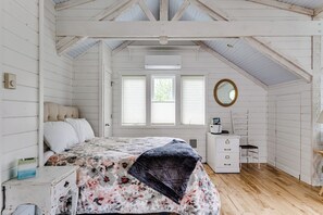 A bedroom with a bed, dresser, mirror, and windows. - Waterfront Studio Apartment w/ Balcony & Lake (Veneta)
