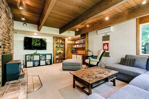 A cozy living room with a fireplace, bookshelves, a television, and comfortable seating. - Scenic Eugene Home w/ Deck 1mi to UofO (Eugene)