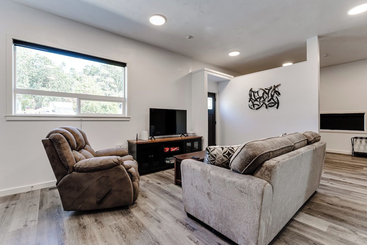 A modern living room with a large window, a flat-screen TV, and a sofa.