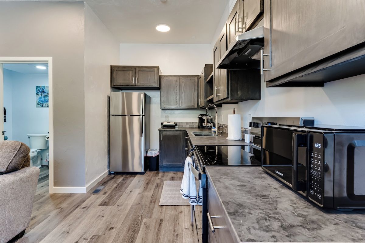 A modern kitchen with stainless steel appliances, wooden cabinets, and a marble countertop.