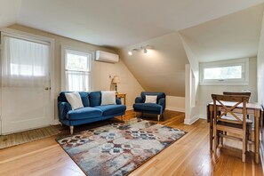 Ein Wohnzimmer mit blauem Sofa, einem passenden Sessel, einem Holzesstisch und einem gemusterten Teppich.