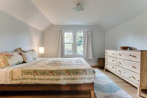 Ein Schlafzimmer mit Bett, Schminktisch, Fenster und Deckenleuchte.