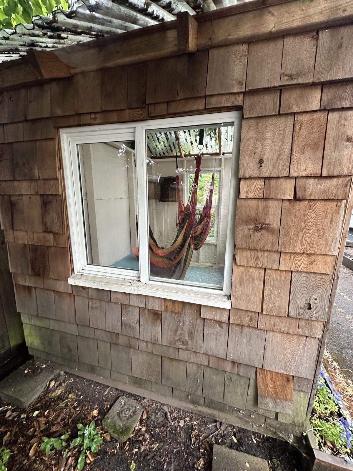 A wooden structure with a window and a hammock inside.