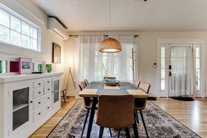 Ein Essbereich mit Holztisch, Stühlen, einer Hängeleuchte und einem weißen Schrank mit Schubladen.
