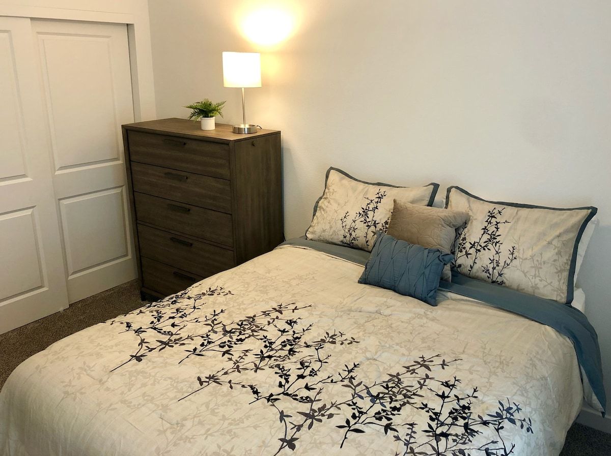 Une chambre à coucher avec un lit, une commode et une table de chevet avec une lampe.