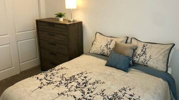 Une chambre à coucher avec un lit, une commode et une table de chevet avec une lampe.