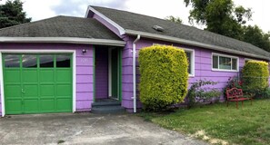 Ett envåningshus med en grön garagedörr, en huvudentré och siffran ’127’ på väggen.