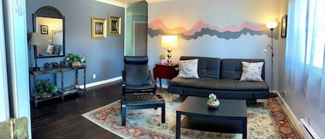 A living room with a sofa, armchair, coffee table, and a decorative rug.