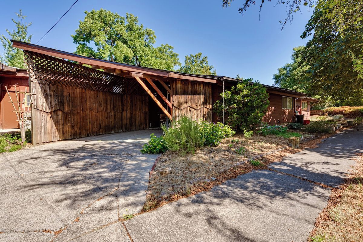 A rustic wooden building with a covered porch and a paved driveway.