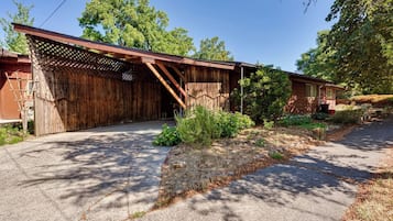 A rustic wooden building with a covered porch and a paved driveway.