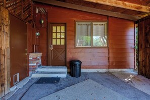 A wooden house entrance with a brown door, a window, and a black trash bin. - Central Eugene Studio w/ Smart TV & Parking (Eugene)