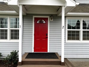 A house with a red door, white siding, and a porch with steps leading to the door. - Comfortable Apartment in a Convenient location. (Springfield)