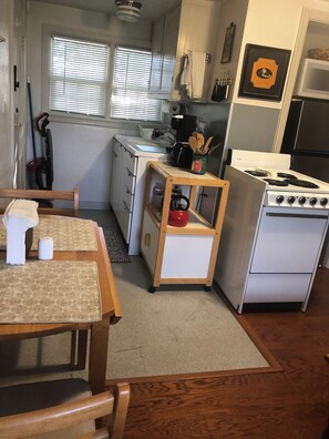 A compact kitchen with a stove, sink, and wooden table. - Comfortable Apartment in a Convenient location. (Springfield)