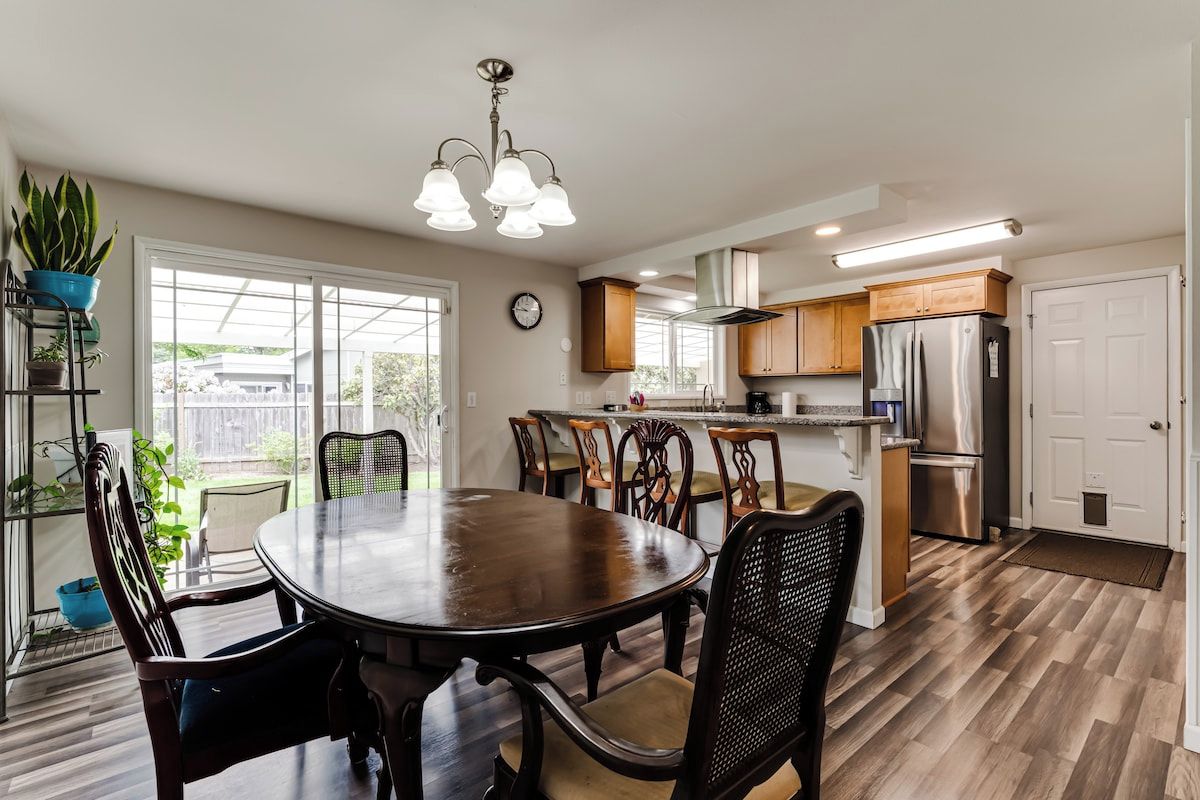 A modern kitchen with a dining table, chairs, and a refrigerator.