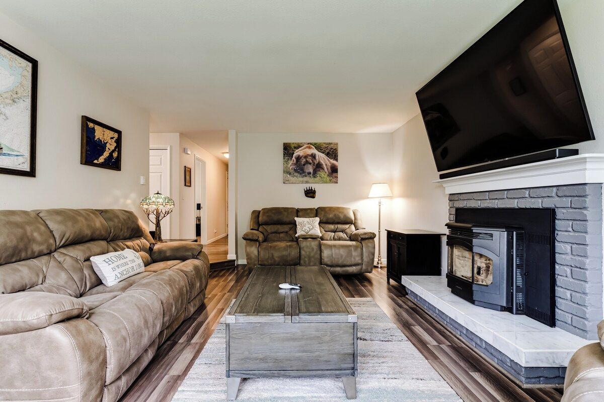 A living room with a fireplace, leather sofas, a coffee table, and a flat-screen TV.