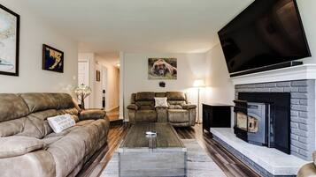 A living room with a fireplace, leather sofas, a coffee table, and a flat-screen TV.