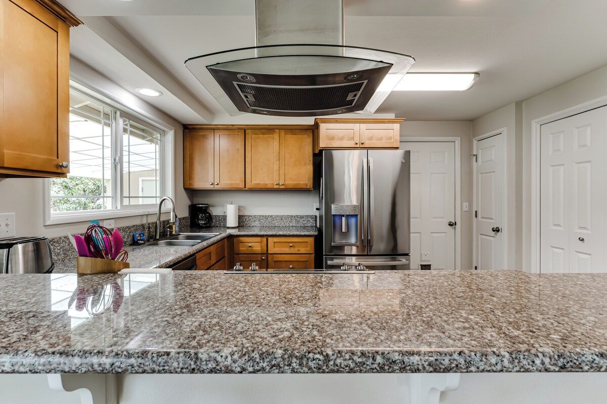 A modern kitchen with granite countertops, stainless steel appliances, and wooden cabinets.