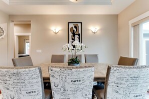 A dining area with a table, chairs, and a wall-mounted light fixture. - Luxury Pool Table House Near UO & Airport (Eugene)