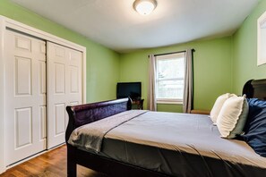 A bedroom with a bed, a television, a window with curtains, and a wardrobe. - Central Home, Covered Deck Near Whiteaker District (Eugene)