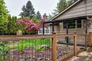 A residential property with a fenced garden area, a wooden deck, and a house with a chimney. - Central Home, Covered Deck Near Whiteaker District (Eugene)