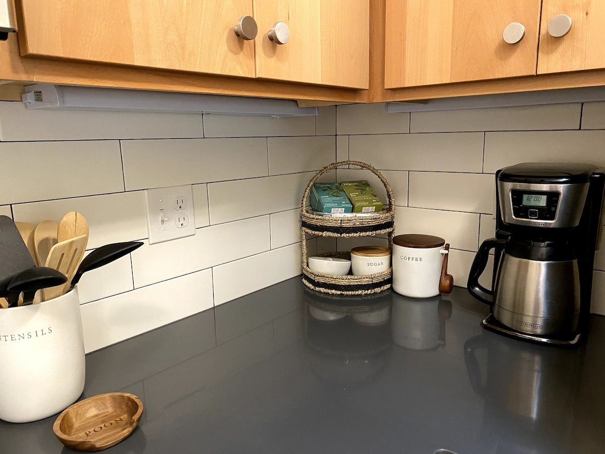 A kitchen with wooden cabinets, a coffee maker, and a spice rack.