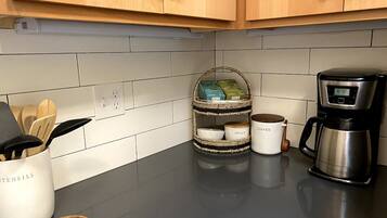 A kitchen with wooden cabinets, a coffee maker, and a spice rack.