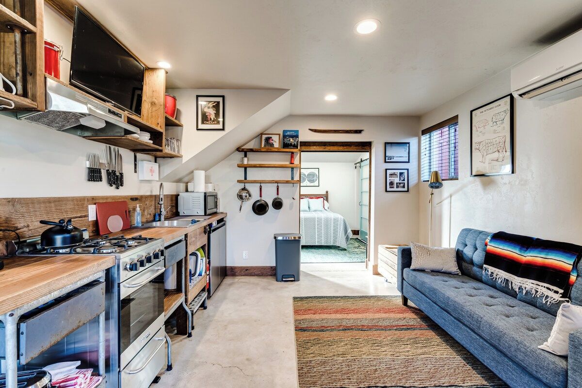 A compact kitchen with a stove, oven, and wooden shelves.