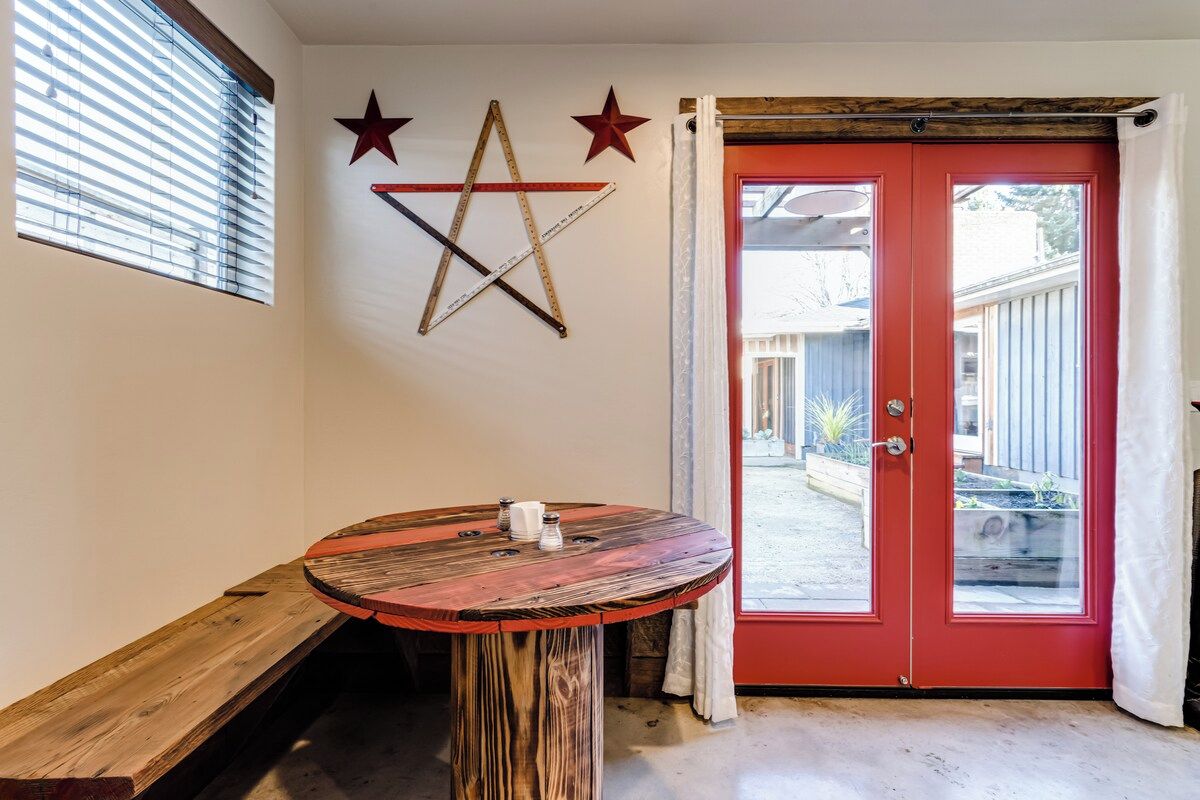 A room with a red door, a round wooden table, and a bench.