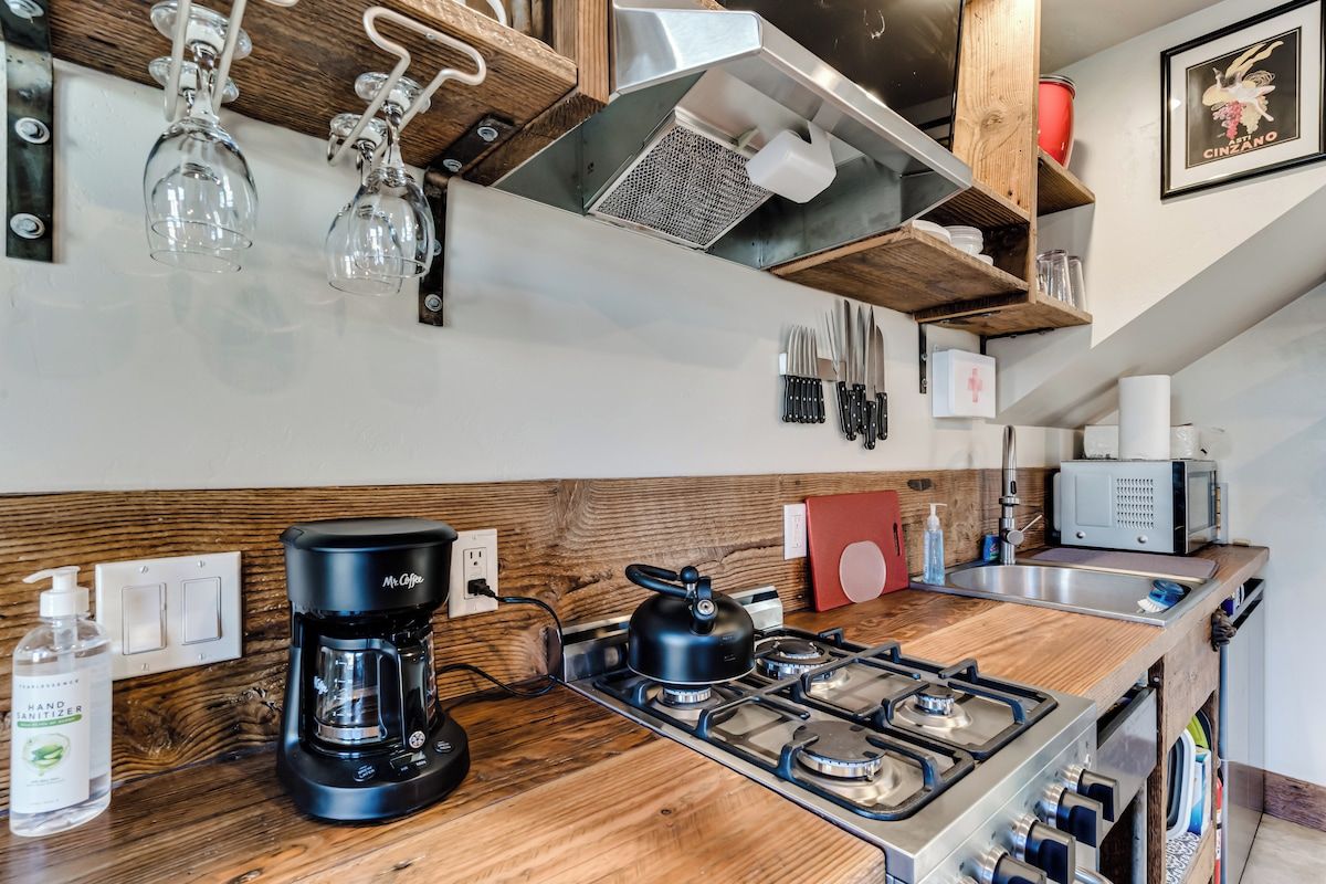 A kitchen with a wooden countertop, a coffee maker, a kettle, and a microwave.