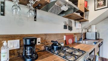Cozinha com bancada de madeira, cafeteira, chaleira e micro-ondas.